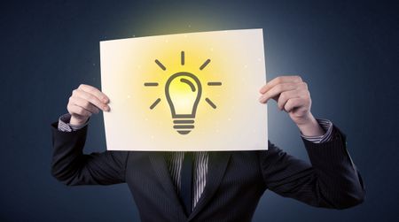 Young businessman hiding behind a lightbulb drawn on paper