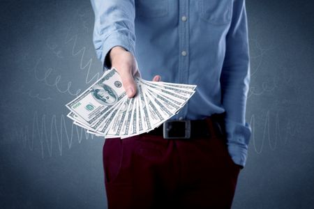 Young businessman holding large amount of bills with grungy background
