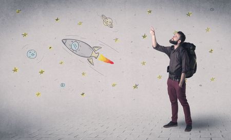 Handsome young man standing with a backpack with space related drawings in the background