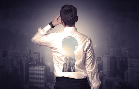 Young businessman standing and thinking with keyhole on his back and city graphic around