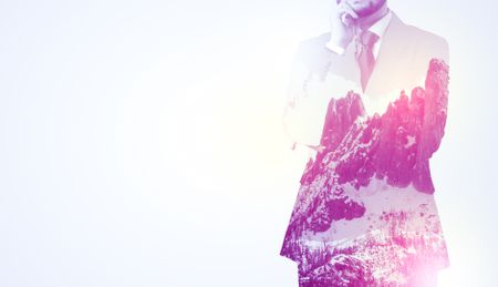  Young businessman in suit standing with sunny snowy mountain and trees graphic.