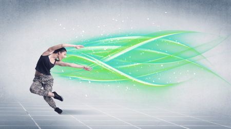 A good looking fresh street dancer dancing in front of grey background with white and bright, colorful green lines concept