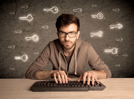 A young internet geek working online, hacking login passwords of social media users concept with glowing drawn keys on the wall