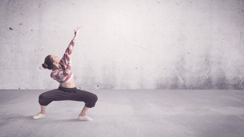 A beautiful young hip hop dancer dancing contemporary urban street dance in empty clear grey wall background concept.