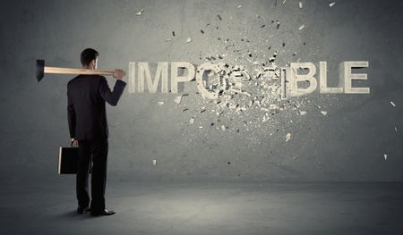 Business man hitting impossible sign with hammer on grungy wall