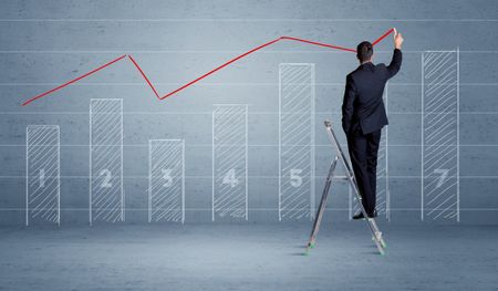 A man in elegant suit standing on a small ladder and drawing a chart on blue wall background with numbers, lines, blocks,