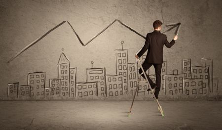 A man in elegant suit standing on a small ladder and drawing a line on brown wall background with buildings