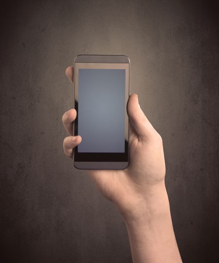 Caucasian hand in business suit holding a blank screen smartphone
