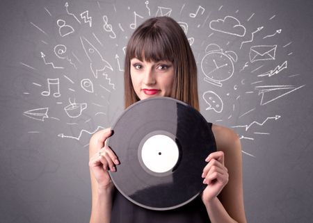 Young lady holding vinyl record on a grey background with mixed scribbles behind her