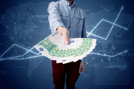 Young businessman holding large amount of bills with blue charts in the background