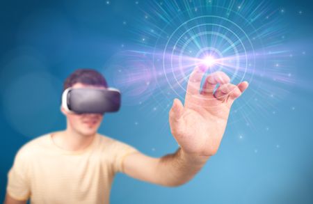 Young impressed man wearing virtual reality goggles with blue circles around his finger 