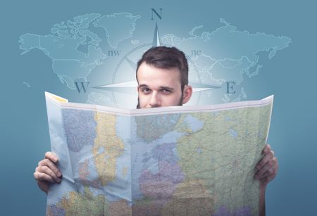 handsome-young-man-holding-map-world-636058826 Handsome young man holding a map with a world map and a compass behind him