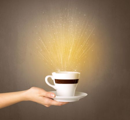 Young female hand holding coffee cup with a beam of light rising out of it 