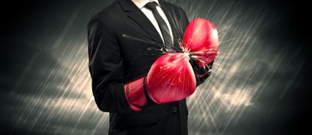 An elegant businessman dressed in suit clashing the boxing gloves on his hand with sparkle concept.
