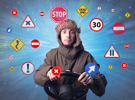 Young man holding black steering wheel with road signs surrounding him