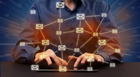 Businessman in suit typing with connected mail icons around 