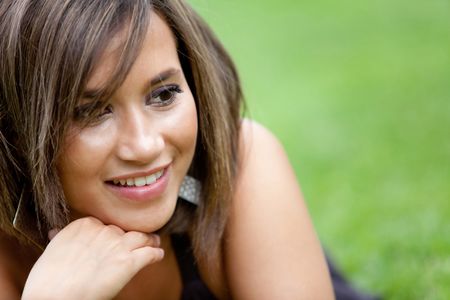 Beautiful woman portrait smiling outdoors lying on grass