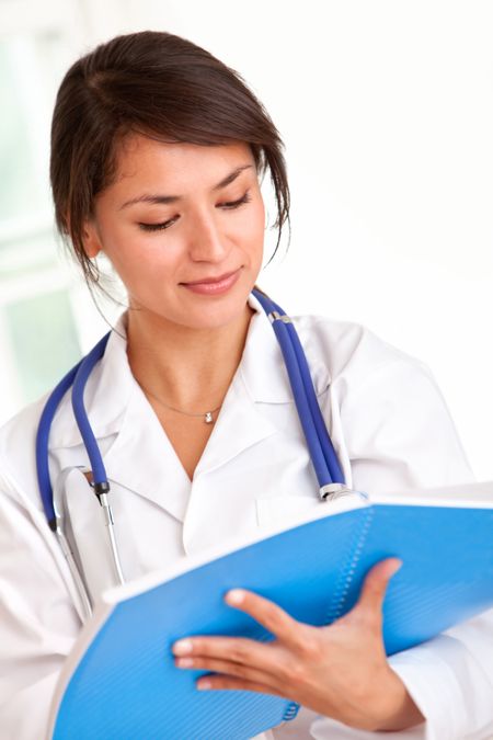 Young female doctor writing on a folder at her practice