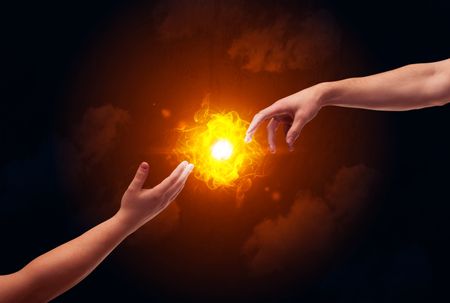 Two naked male hands about to touch, lighting a bright flame with smoke in red sky background concept