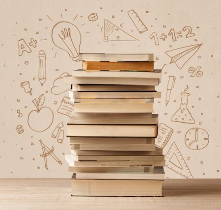 A pile of books on table with school hand drawn doodle sketches and symbols