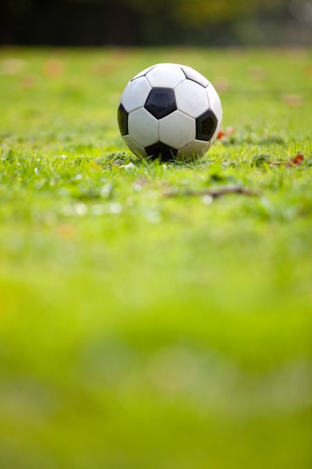 Football or soccer ball on a green lawn - outdoors