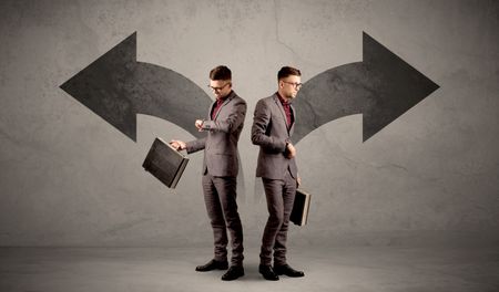 Young conflicted businessman choosing between two directions represented by black arrows