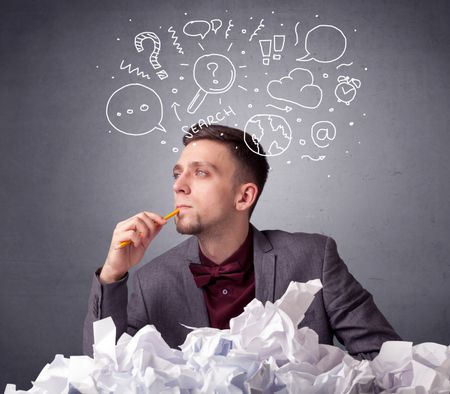 Young businessman sitting behind crumpled paper with mixed doodles over his head