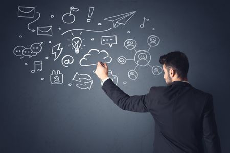 Young businessman in black suit standing in front of white mixed media icons