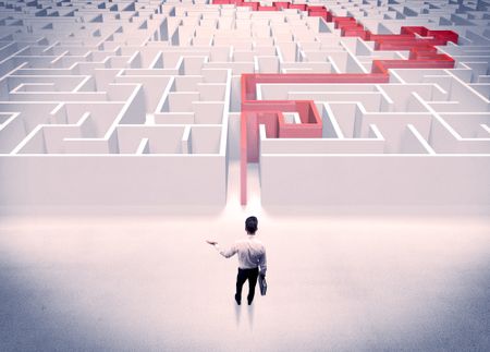 A businessman in suit giving thumbs up in front of labyrinth with red line showing the way out