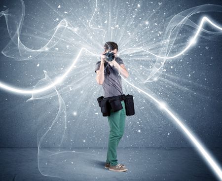 A young amateur photographer with professional photographic equipment taking picture in front of blue wall with dynamic white lines illustration concept