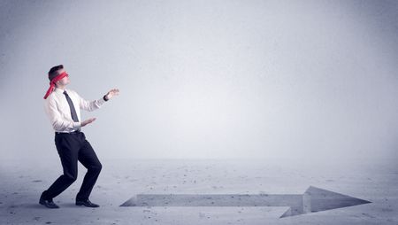 A confused blind salesman standing in front of a drawn arrow on the floor pointing in the right direction concept.