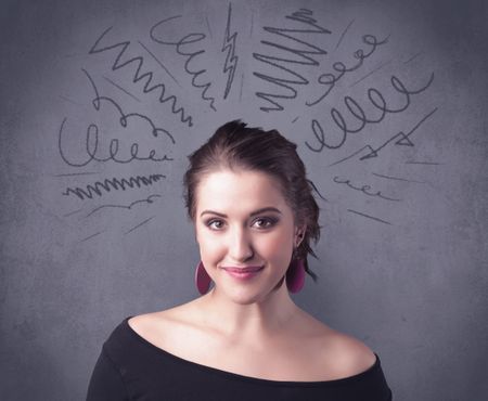 A cute female student making funny face expressions with pressure and problems in her head illustrated by drawn lines, marks and spirals on the urban wall background concept.