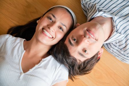 Young couple lying on the floor with heads together