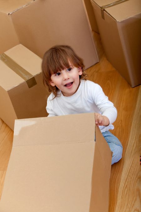 Kid playing with cardboard boxes and smiling