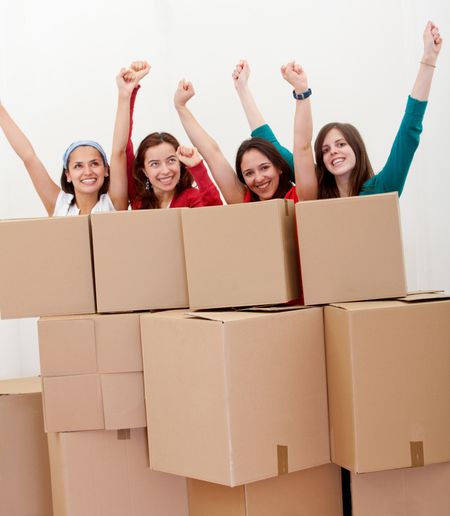 Happy group of women with cardboard boxes moving into a new house .
