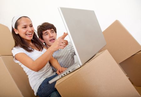 Couple with a laptop and packing into cardboard boxes
