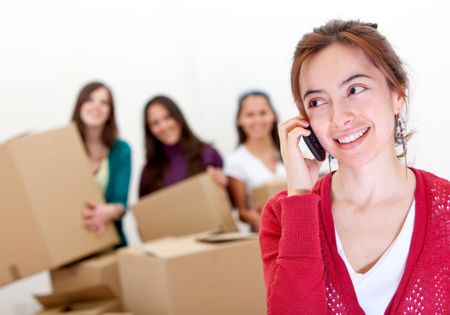 Group of girls calling the moving van while packing in boxes