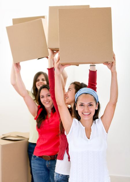 Happy group of women with cardboard boxes moving into a new house