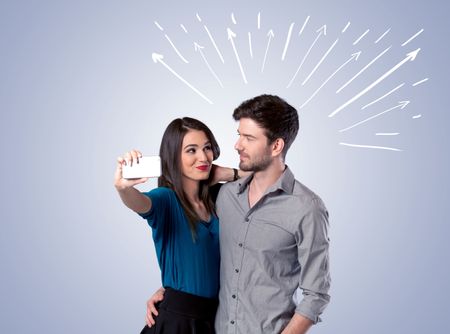 A cheerful young couple taking selfie photo with mobile phone and white lines and arrows pointing to the sky above them concept