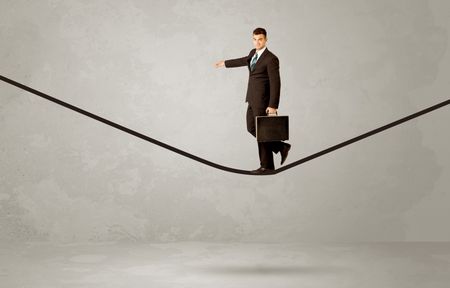 An elegan businessman in suit balancing on a tight rope with a