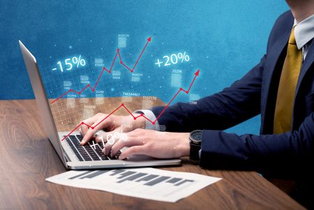 An elegant businessman working on graph statistics calculation using a laptop with clear blue background concept