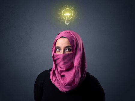 Young muslim woman wearing niqab with lit lightbulb above her head