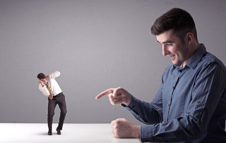 Young professional businessman being angry with an other miniature businessman in front of a splattered background