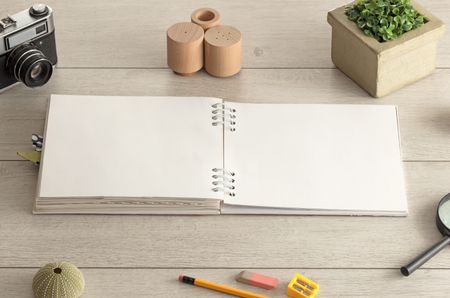 Empty notebook on wood floor with office tools nearby