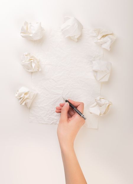 Female hand trying to write next to a few crumpled paper balls