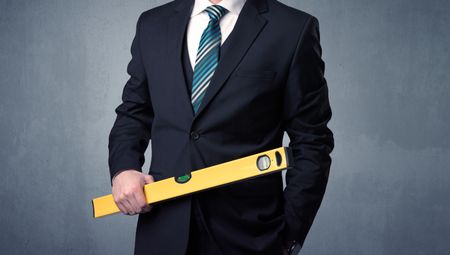 Young, handsome, cute businessman holding tool with grey background