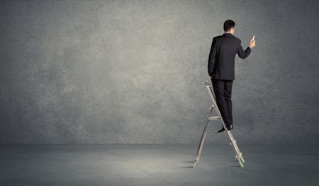 A man standing on ladder drawing with chalk in his hand on clear wall pattern background