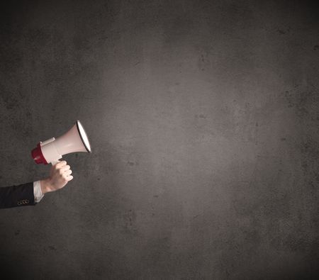 Caucasian arm holding megaphone with plain grunge background