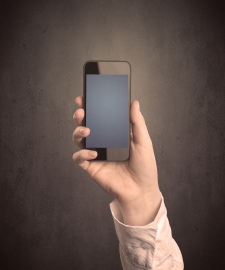 Caucasian hand in business suit holding a blank screen smartphone