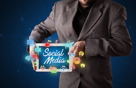 Casual businessman holding tablet with social media icons